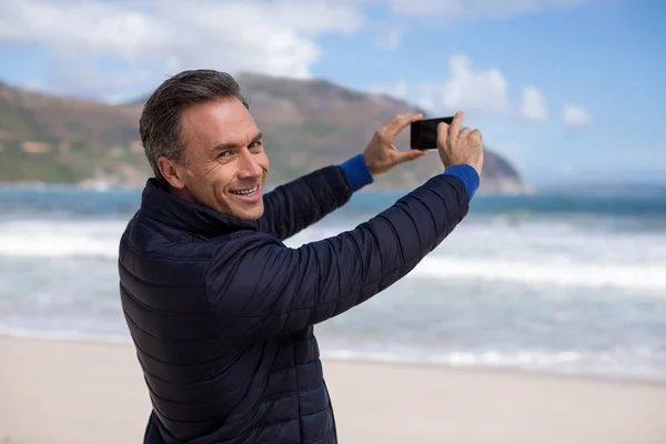 Maduro homem fotografar paisagem usando telefone celular na praia — Fotografia de Stock