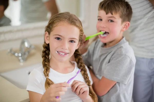 Broers en zussen tandenpoetsen in de badkamer — Stockfoto