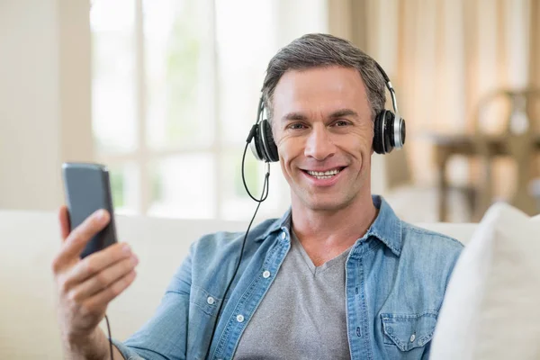 Hombre escuchando música en auriculares en la sala de estar en casa —  Fotos de Stock