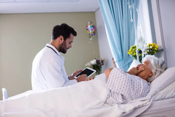 Medico di sesso maschile che discute il rapporto medico su tablet digitale con paziente anziana di sesso femminile nel reparto — Foto Stock