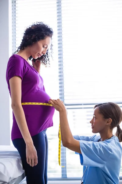 Doctor measuring pregnant womans belly in ward — Stock Photo, Image