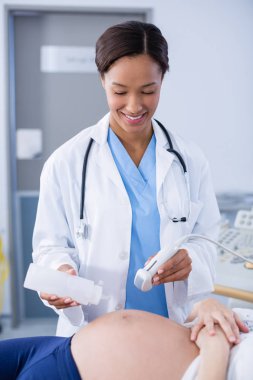 Doctor doing ultrasound scan for pregnant woman clipart