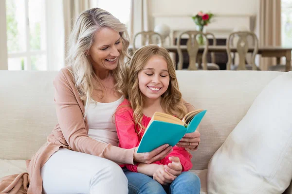 Mother and daughter reading a novel on the couch — Stock Photo, Image