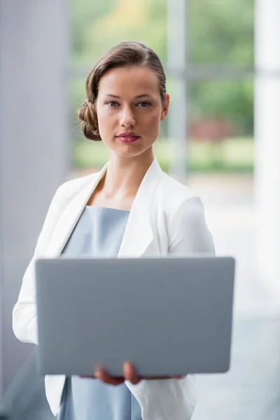 Confident businesswoman holding laptop at conference centre — Stock Photo, Image