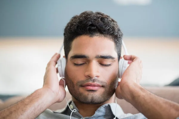 Man luistert naar muziek op koptelefoon in de woonkamer — Stockfoto