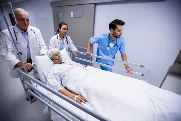 Médico e enfermeira empurrando cama maca de emergência no corredor — Fotografia de Stock