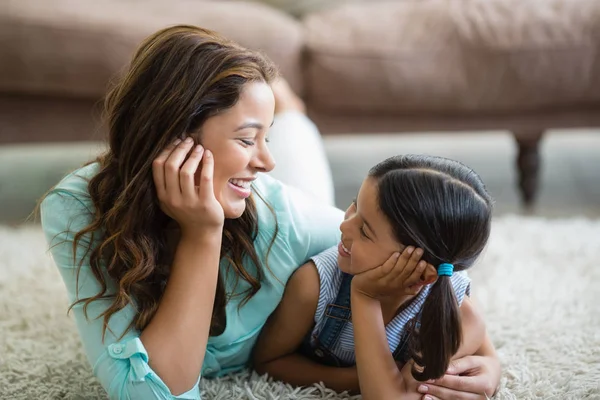 Glückliche Tochter und Mutter interagieren miteinander, während sie auf Teppich liegen — Stockfoto