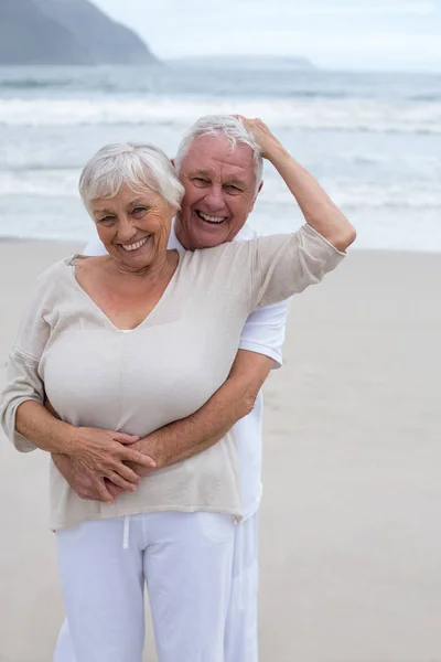 Senior paar omhelzen elkaar op het strand — Stockfoto