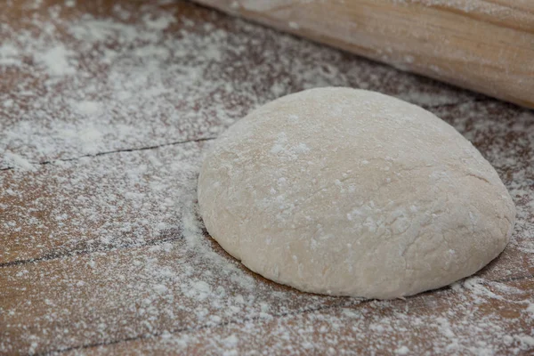 Rolling pin with pizza dough and flour on rolling board — Stock Photo, Image