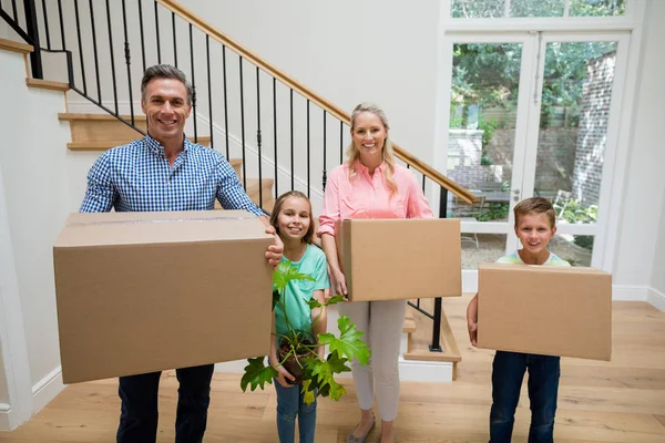 Genitori e bambini che tengono scatole di cartone in soggiorno a casa — Foto Stock