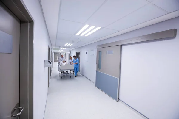 Team of doctors taking senior woman to the operation theatre in the corridor — Stock Photo, Image