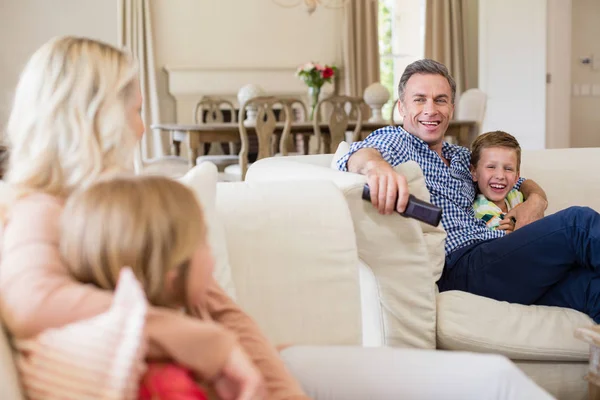 Familjen som interagerar med varandra medan du tittar på tv i vardagsrummet — Stockfoto
