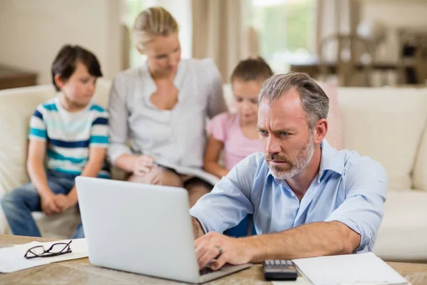 Man using laptop with bills on table in living room — Stock Photo, Image