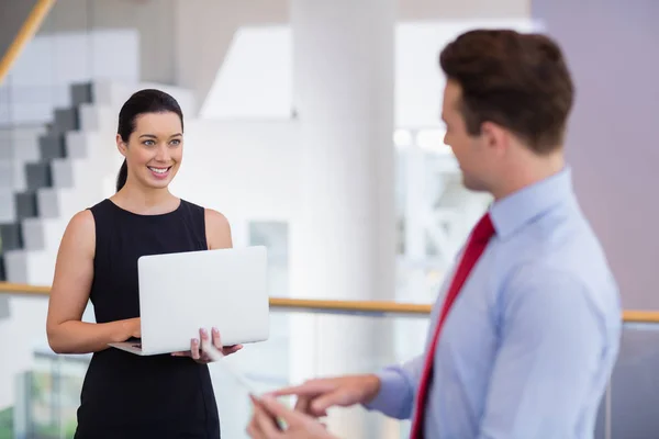 Businesswoman holding laptop and interacting with colleague — Stock Photo, Image