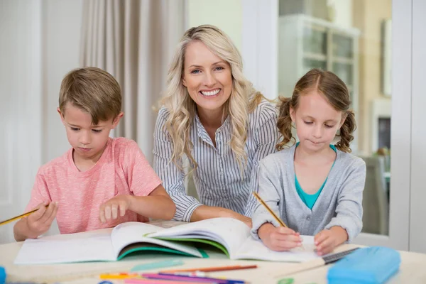 Mère aidant les enfants à faire leurs devoirs — Photo