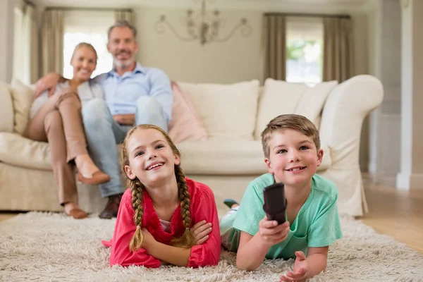 Rodiče a děti dívat se na televizi v obývacím pokoji — Stock fotografie