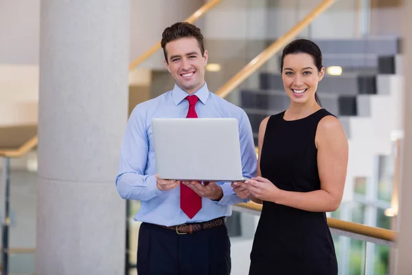 Happy business executives holding a laptop — Stock Photo, Image