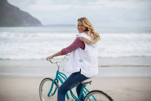Mature woman riding bicycle on the beach — Stock Photo, Image
