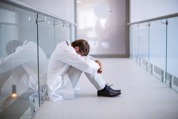 Напряженный доктор сидит в коридоре — стоковое фото