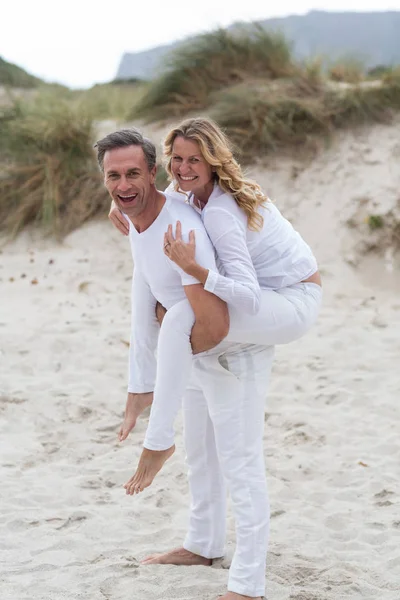 Reifer Mann gibt Huckepack-Fahrt zu Frau am Strand — Stockfoto