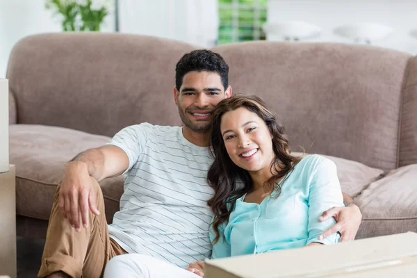 Lyckliga paret sitter med arm runt i vardagsrummet — Stockfoto