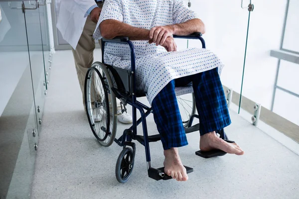 Врач несет пациента на инвалидной коляске — стоковое фото