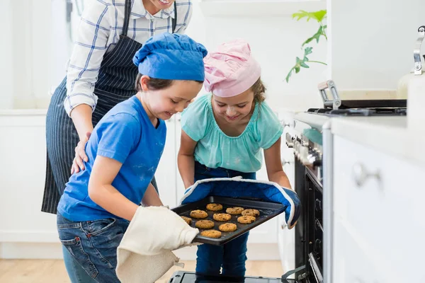 Sourozenci umístění zásobníku souborů cookie v troubě — Stock fotografie