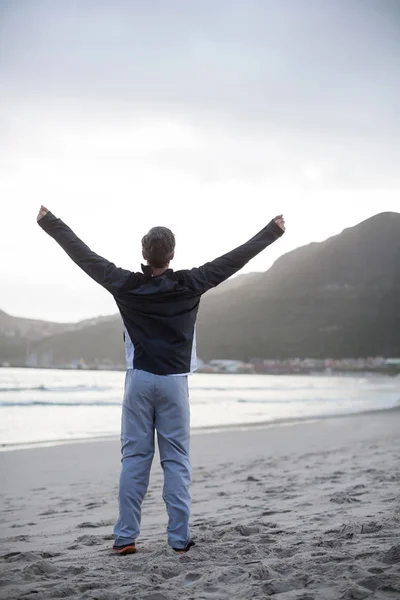 Зрелый мужчина, стоящий с распростертыми на пляже руками — стоковое фото
