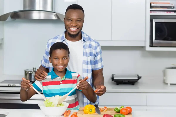 Padre e hijo preparando ensalada en la cocina en casa — Foto de Stock