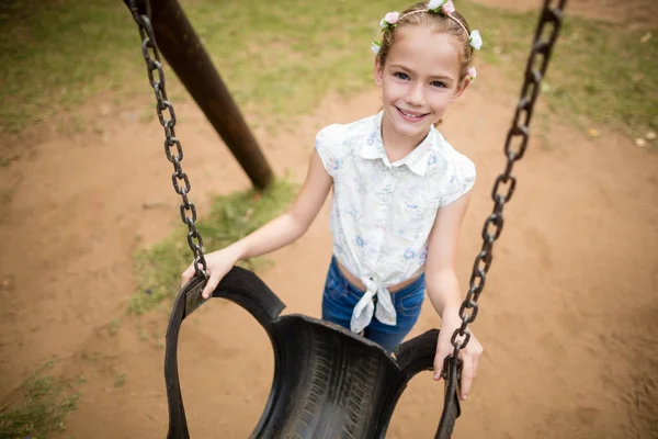 Happy girl smiling while holding a swing in park — Stock Photo, Image