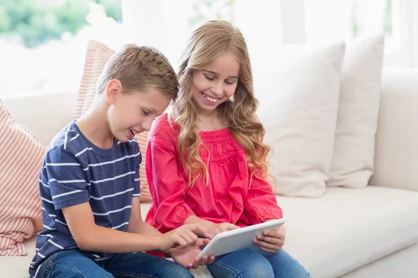 Geschwister nutzen digitales Tablet auf Sofa im Wohnzimmer — Stockfoto