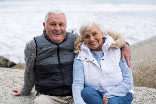 Seniorenpaar sitzt am Strand auf einem Felsen — Stockfoto