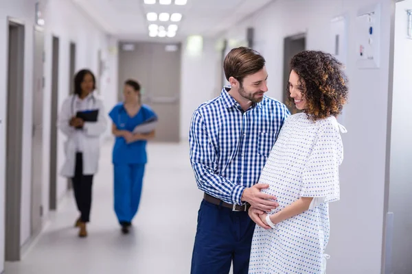 Man comforting pregnant woman in corridor — Stock Photo, Image
