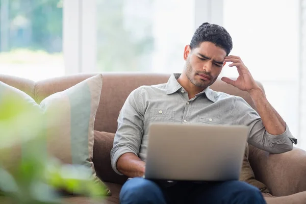 Man zittend op de Bank en met behulp van de laptop in de huiskamer — Stockfoto