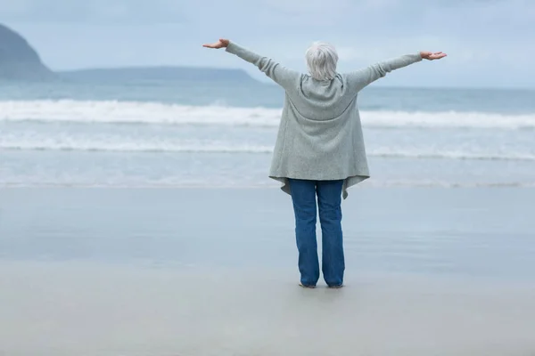 Ώριμη γυναίκα με τα χέρια απλωμένα στέκεται στην παραλία — Φωτογραφία Αρχείου