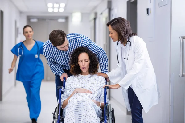 Врач и мужчина утешают беременную женщину в коридоре — стоковое фото