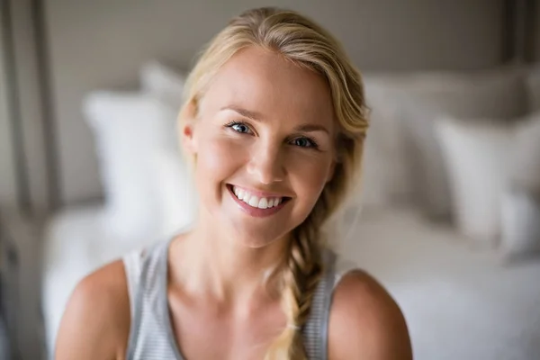 Smiling beautiful woman sitting on bed in bedroom — Stock Photo, Image