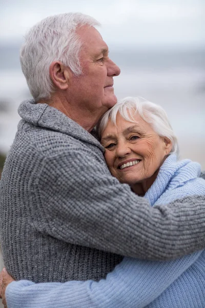 Senior paar omhelzen elkaar op het strand — Stockfoto