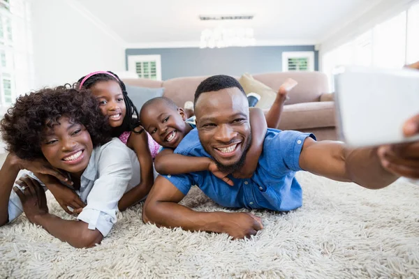 Šťastná rodina s selfie z mobilního telefonu v obývacím pokoji — Stock fotografie