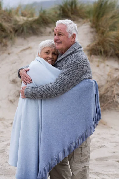 Senior para zapakowane w szal na plaży — Zdjęcie stockowe