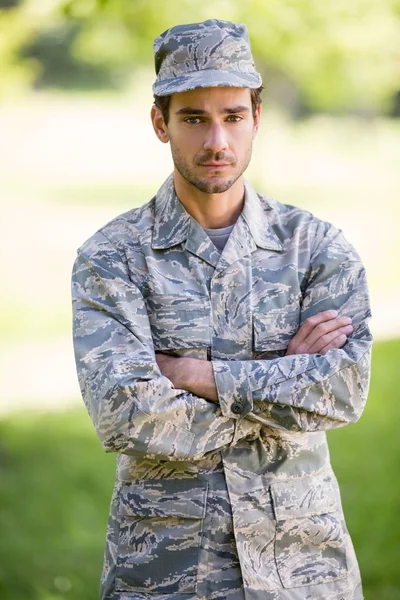 Retrato de soldado de pé com os braços cruzados no parque — Fotografia de Stock