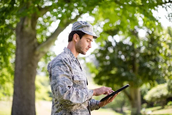 Солдат використовує цифровий планшет у парку — стокове фото