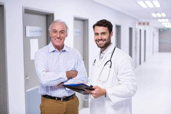 Potret dokter dan pasien yang membahas pada papan klip di koridor — Stok Foto