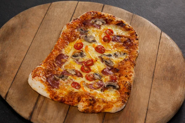 Deliciosa pizza italiana servida sobre tabla de madera — Foto de Stock