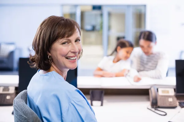 Портрет улыбающейся медсестры, сидящей за столом — стоковое фото