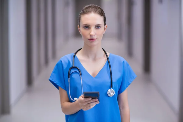 Retrato de médica usando telefone celular no corredor — Fotografia de Stock
