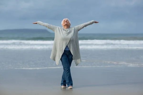 Senior kvinna gör stretching övning på stranden — Stockfoto