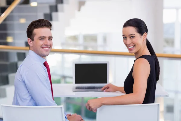 Ejecutivos de negocios felices sentados en el escritorio con computadora portátil — Foto de Stock