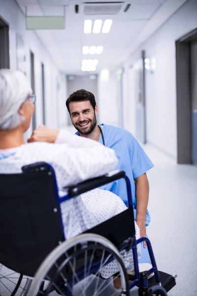 Мужской врач взаимодействует со старшим пациентом на инвалидной коляске — стоковое фото