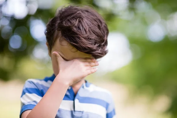 Junge verdeckt Augen mit Hand im Park — Stockfoto